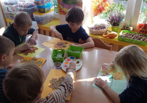 Dzieci malują farbami liście za pomocą patyczków do uszu